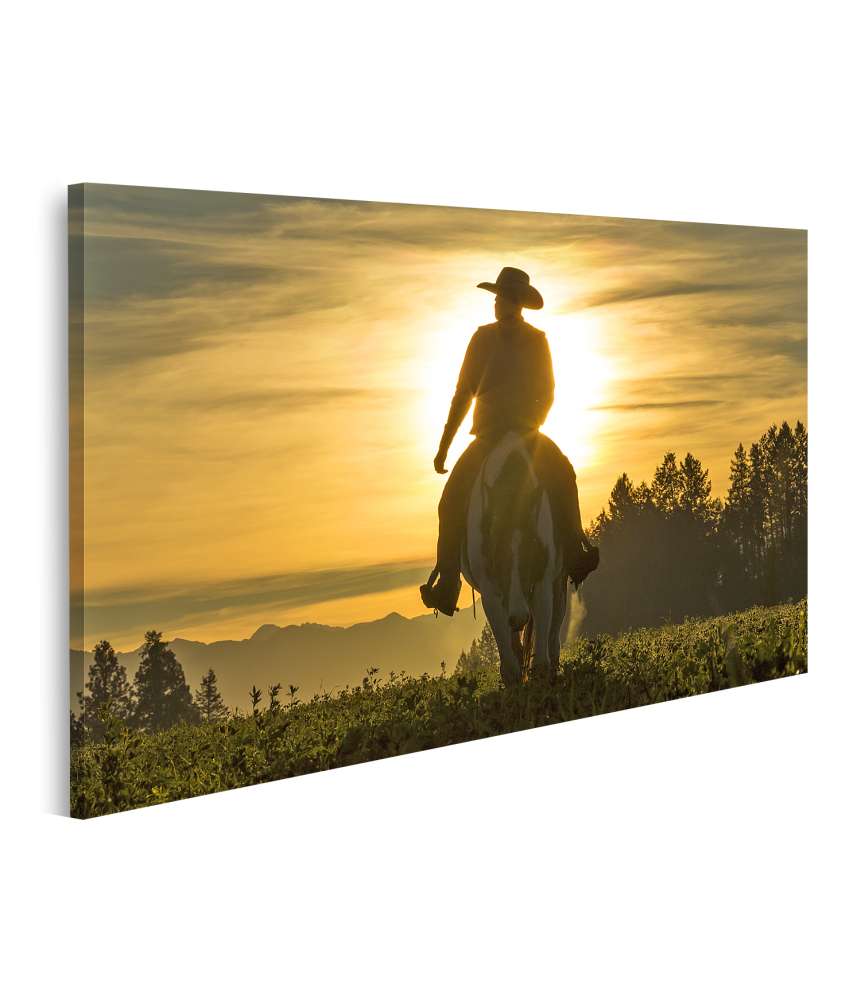 Islandburner Bild auf Leinwand Frühmorgens reitet ein Cowboy über Grasland, Berge und Sonne im Hintergrund