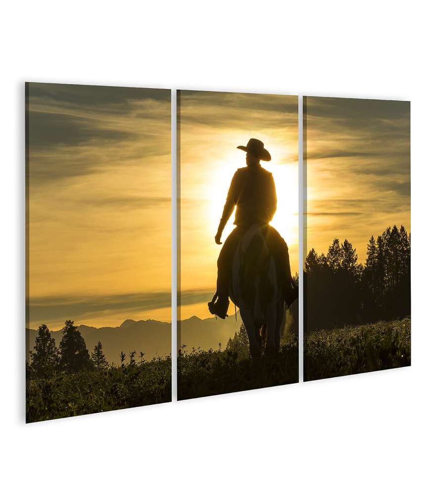 Islandburner Bild auf Leinwand Frühmorgens reitet ein Cowboy über Grasland, Berge und Sonne im Hintergrund